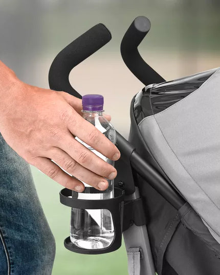 Hand holding a water bottle in a stroller cup holder with a blurred background