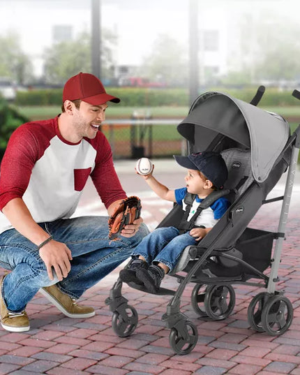 Man playing catch with a child in a stroller outdoors