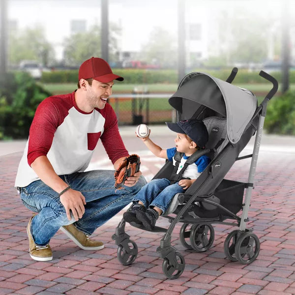 Man playing catch with a child in a stroller outdoors