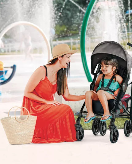 Woman in a red dress sitting next to a child in a stroller by a fountain