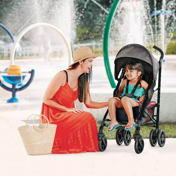Woman in a red dress sitting next to a child in a stroller by a fountain