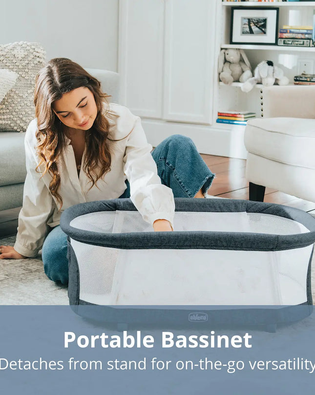 Woman setting up a portable bassinet in a living room.