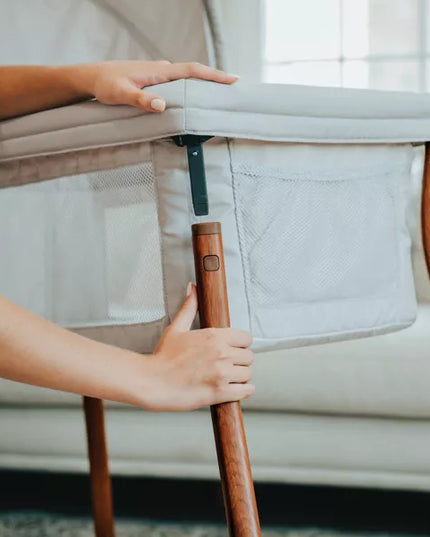 Person adjusting a baby crib with wooden handle