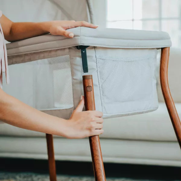 Person adjusting a baby crib with wooden handle