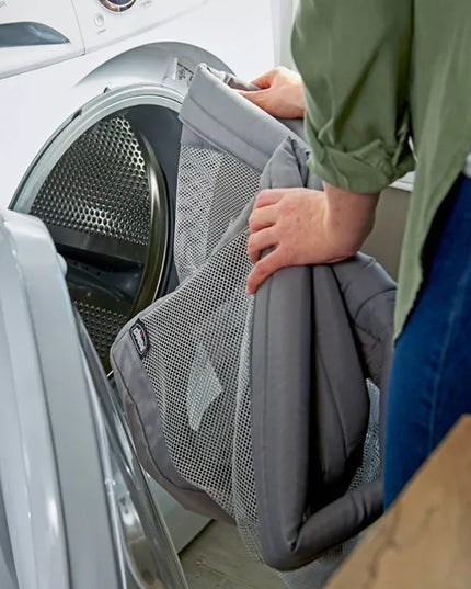 Person placing a baby car seat into a washing machine