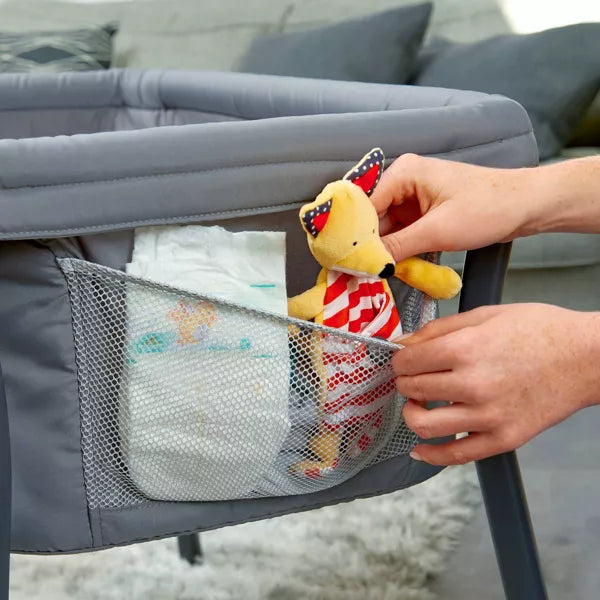 Person placing a plush toy into a mesh pocket of a baby bouncer.