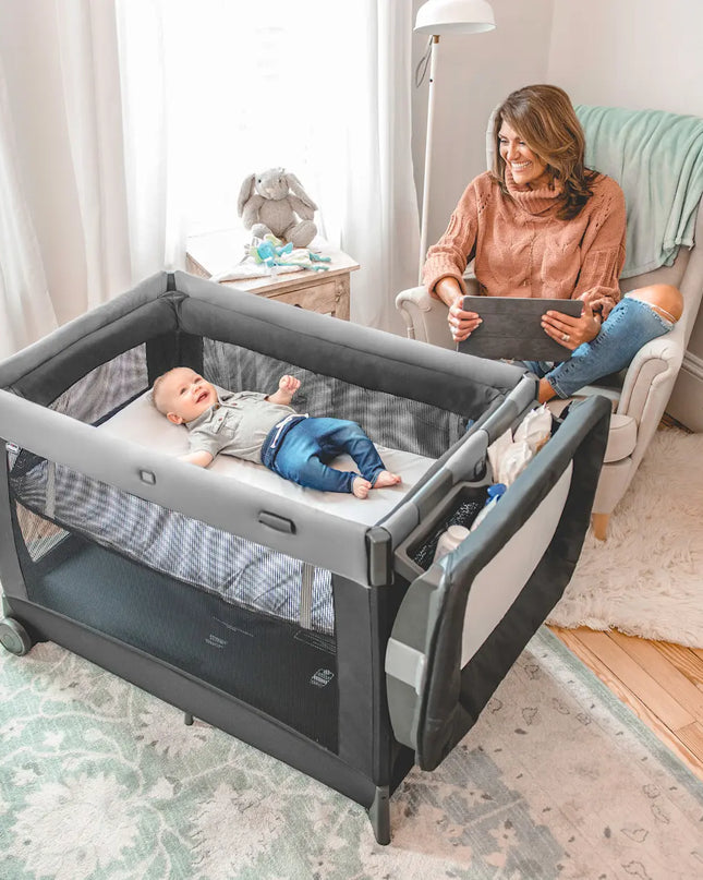 Baby in a crib with a woman sitting nearby in a home setting