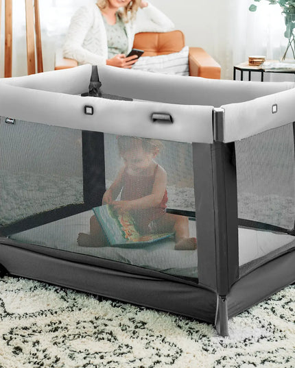Child sitting inside a portable playpen in a living room setting.