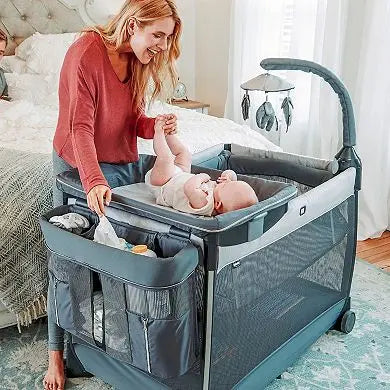 Woman with a baby in a portable crib in a bedroom setting