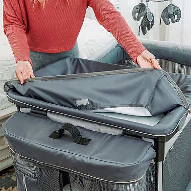 Person folding a gray baby changing table with a red shirt.