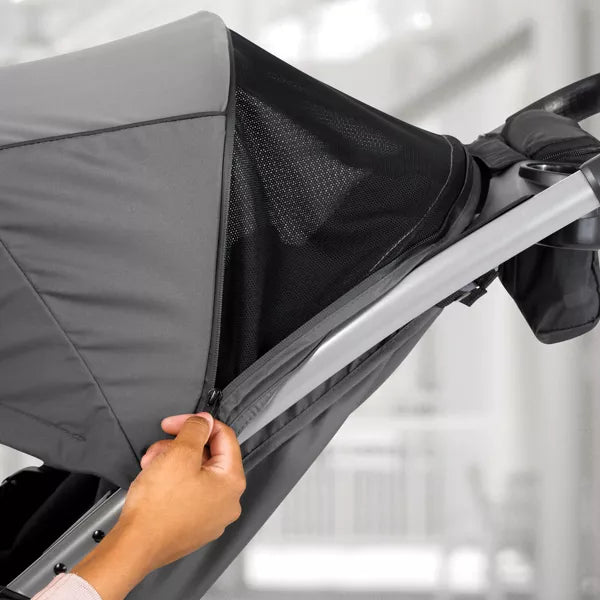 Hand adjusting a gray stroller canopy with a blurred background