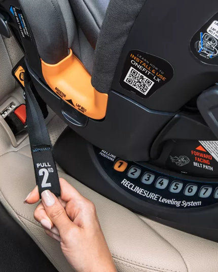 Child car seat with a hand adjusting the strap, showing the 'ReclineSure' leveling system.