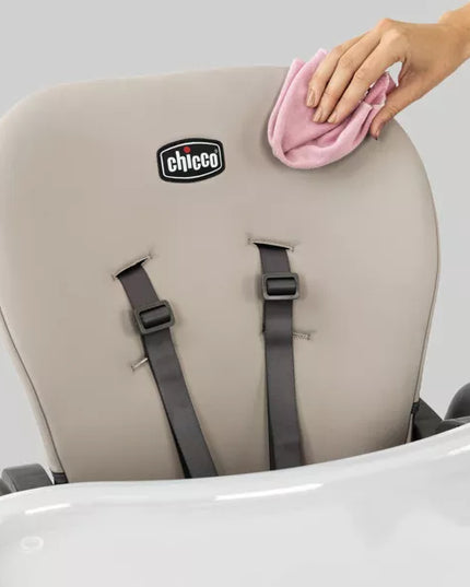 Chicco high chair being cleaned with a pink cloth on a gray background