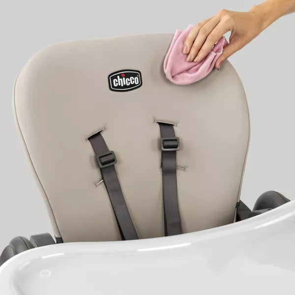 Chicco high chair being cleaned with a pink cloth on a gray background