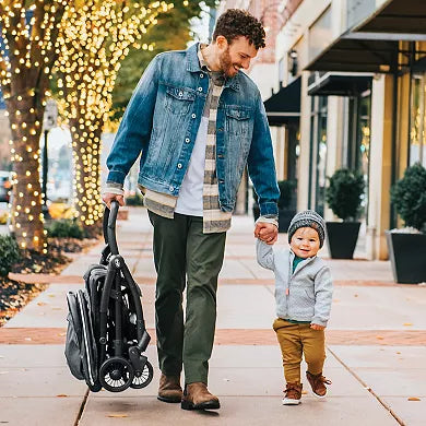 Man and child walking together with a stroller on a sidewalk