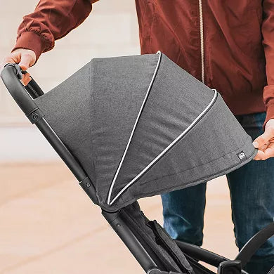 Person holding a gray stroller canopy with a blurred background