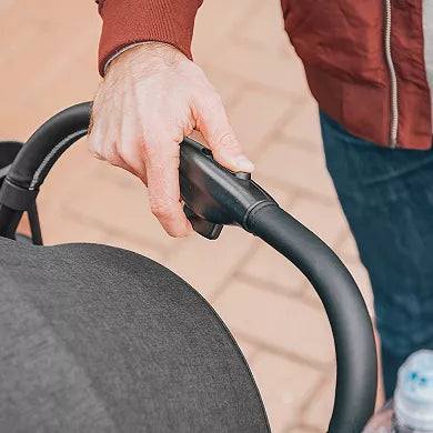 Person holding a stroller handle with a blurred background