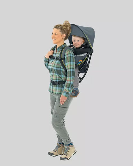Woman carrying a child in a baby carrier against a plain background