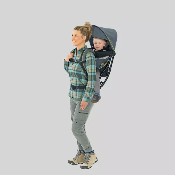 Woman carrying a child in a baby carrier against a plain background