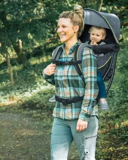 Woman walking outdoors with a child in a backpack carrier