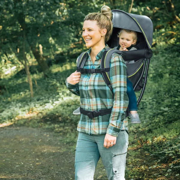 Woman walking outdoors with a child in a backpack carrier