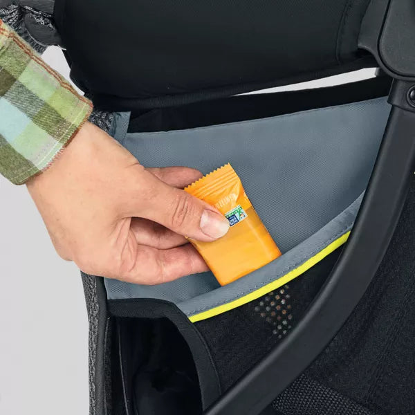 Hand reaching into a car seat pocket to retrieve an orange snack package.