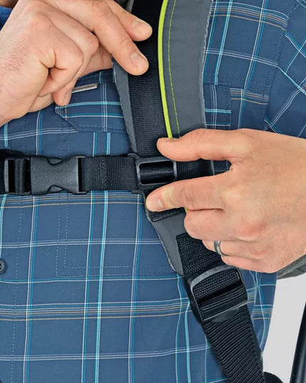Person adjusting a black seat belt on a blue plaid shirt.