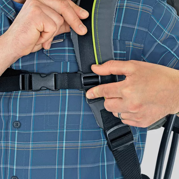 Person adjusting a black seat belt on a blue plaid shirt.