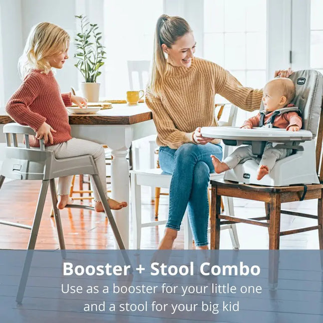 Two women with a child using a booster and stool combo at a dining table.