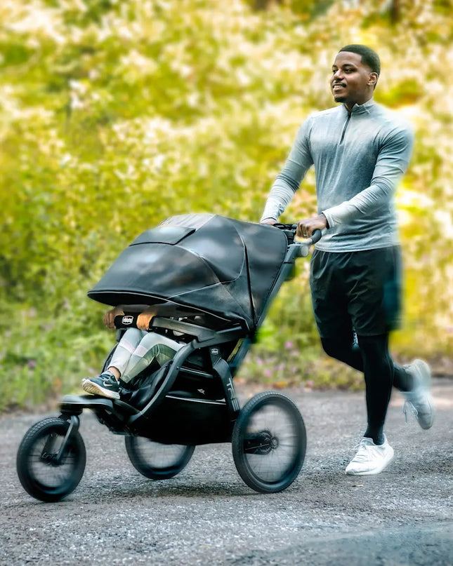 Man pushing a stroller with a blurred natural background