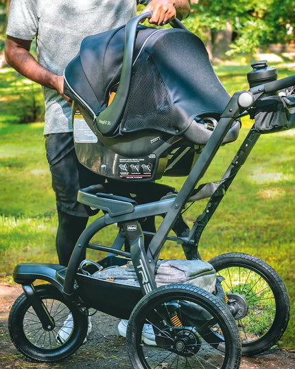 Stroller with a car seat attachment in a park setting