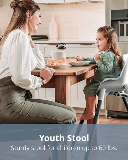 Woman and child at a kitchen table with a high chair, emphasizing the youth stool's use.
