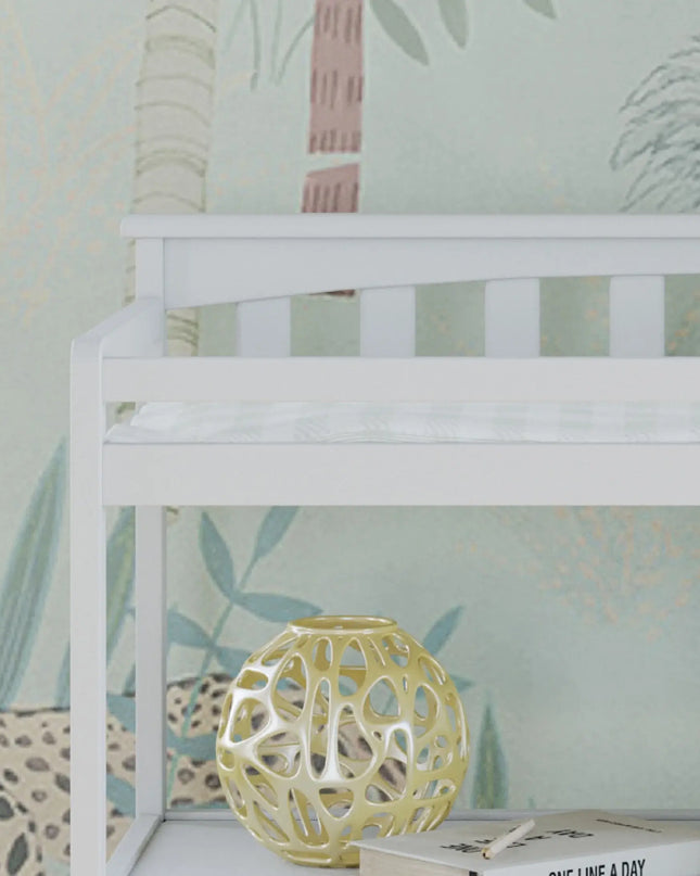 White shelf with a decorative yellow sphere and books against a patterned wallpaper background