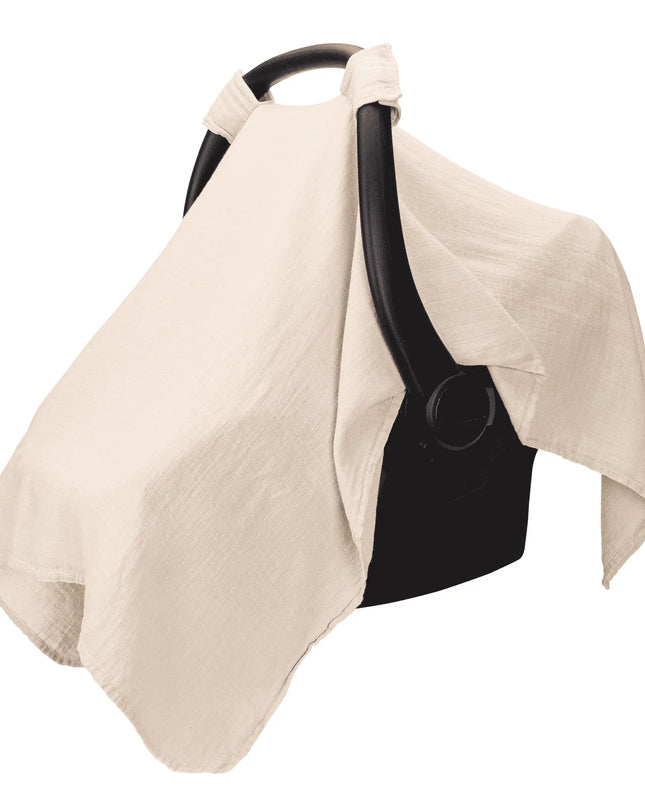 Beige baby car seat cover draped over a black car seat on a white background