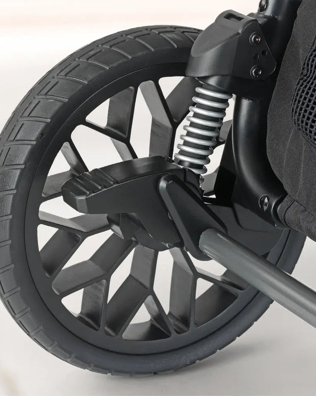 Close-up of a stroller wheel with suspension system on a light background