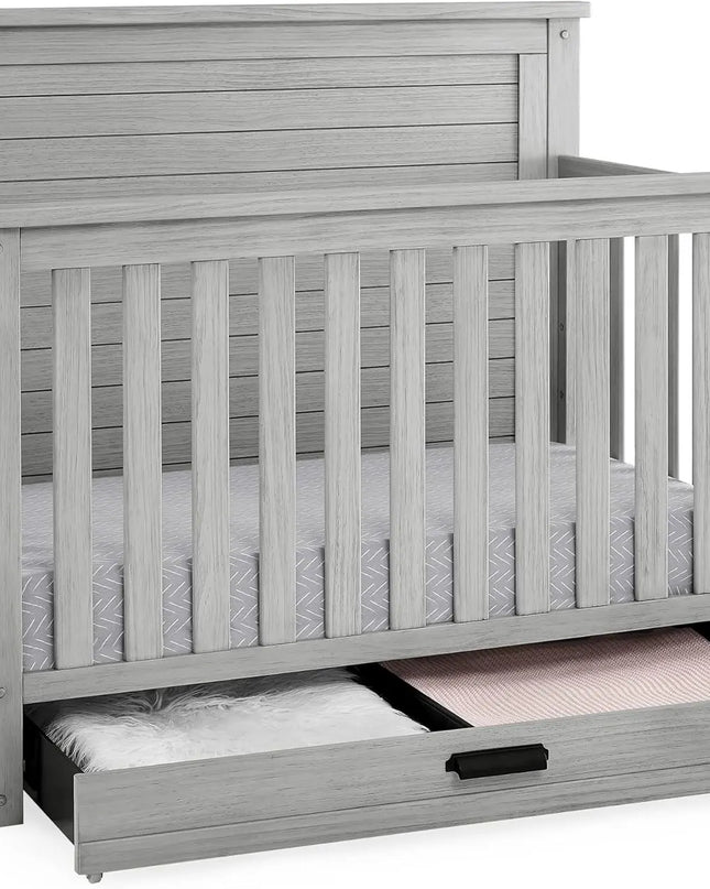 Gray crib with a pull-out drawer on a white background