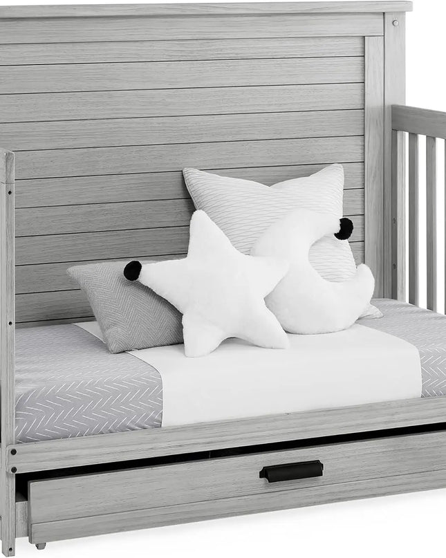 Gray wooden crib with star-shaped pillows and a white blanket on a white background