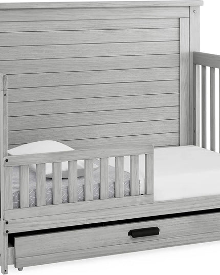 Gray wooden crib with a mattress and drawer extension on a white background