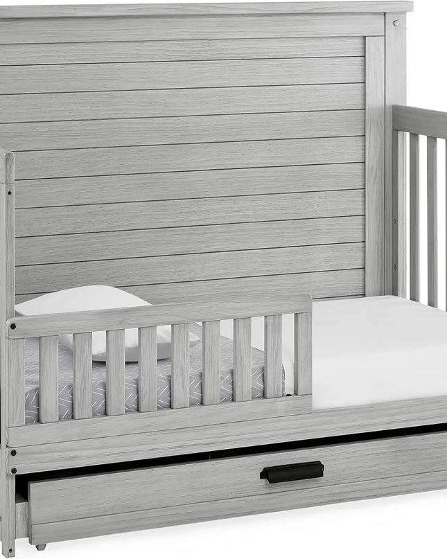 Gray wooden crib with a mattress and drawer extension on a white background