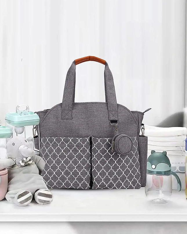 Gray diaper bag with patterned pockets on a white surface with baby items around