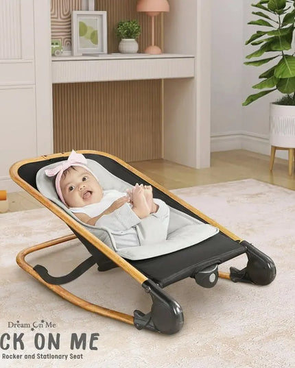 Baby in a rocker seat in a room with a desk and plant
