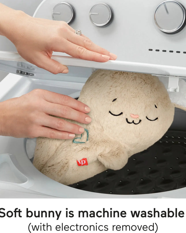 Plush bunny toy with a smiley face being placed into a washing machine, with text indicating it is machine washable.