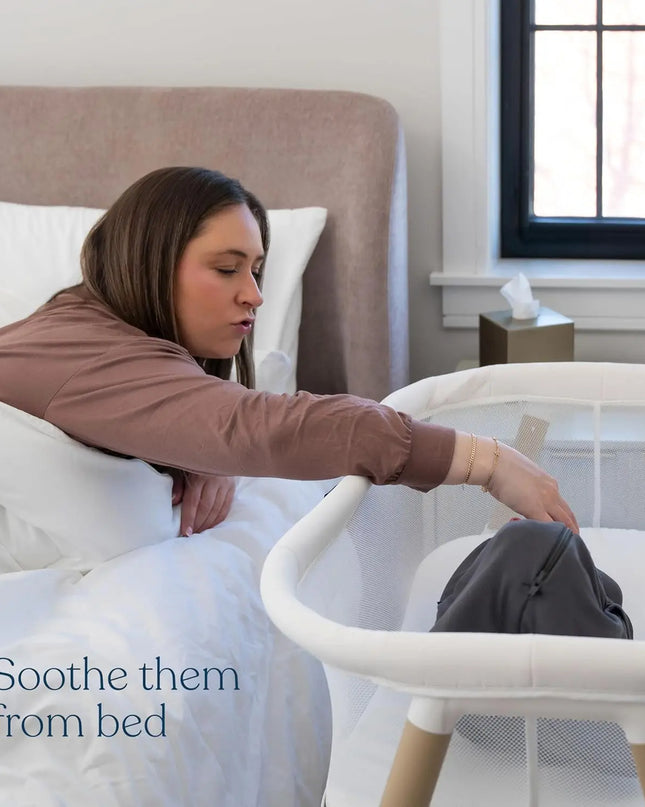 Woman in bed with a baby in a crib next to her, text 'Soothe them from bed'.