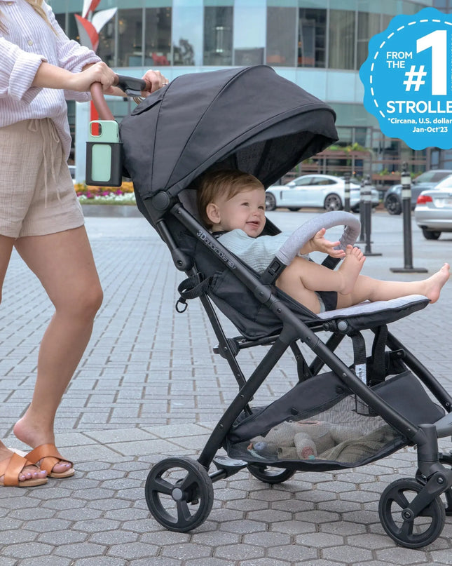 Woman pushing a stroller with a child sitting inside on a sidewalk.