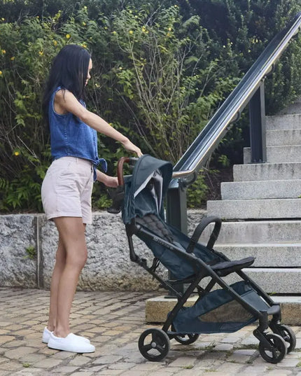Woman pushing a stroller outdoors near steps and greenery