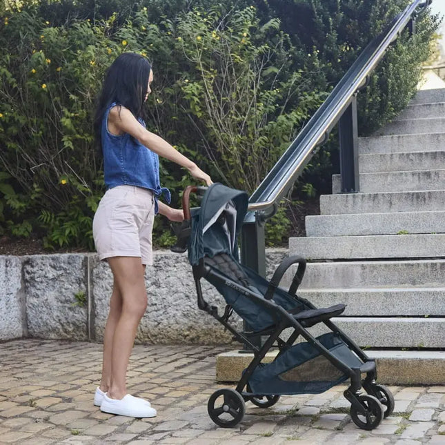 Woman pushing a stroller outdoors near steps and greenery
