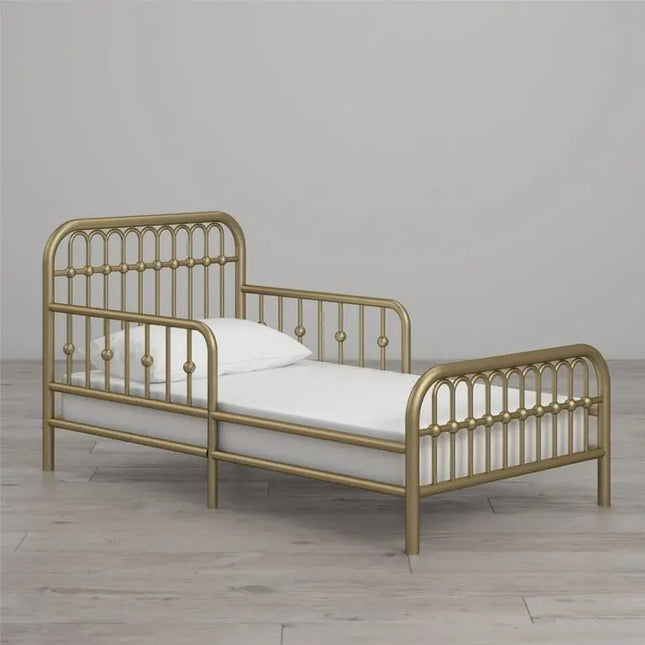 Gold metal bed frame with white mattress and pillow on a wooden floor.