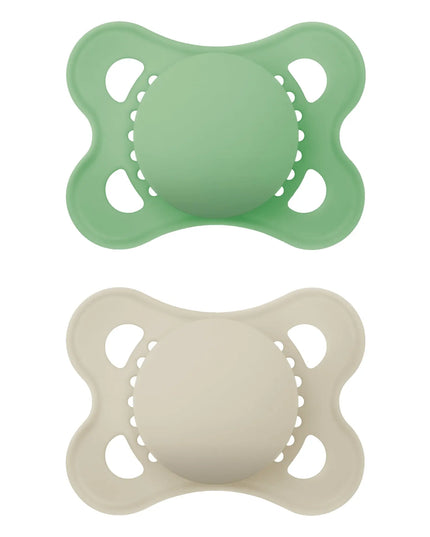Two silicone pacifiers, one green and one beige, on a white background.