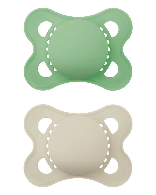 Two silicone pacifiers, one green and one beige, on a white background.