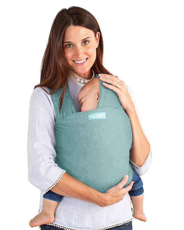 Woman holding a baby in a green Moby baby carrier against a white background